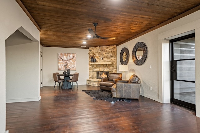 living room featuring a stone fireplace, dark hardwood / wood-style floors, wooden ceiling, and ceiling fan