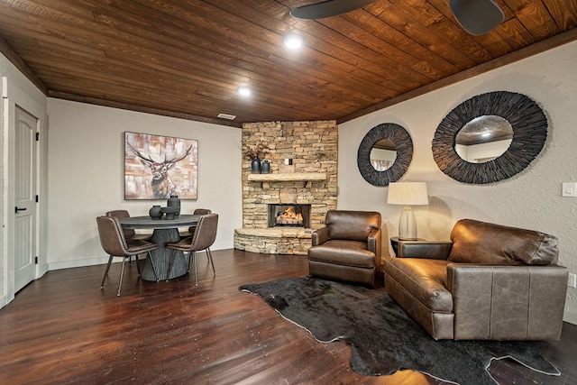 living room featuring dark hardwood / wood-style flooring, a stone fireplace, and wood ceiling