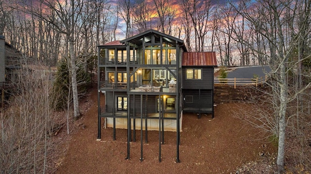 back house at dusk featuring a balcony