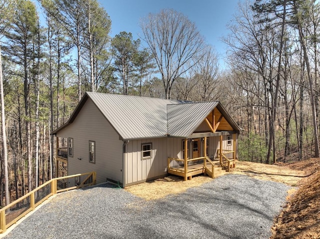 exterior space with metal roof, covered porch, board and batten siding, and a wooded view