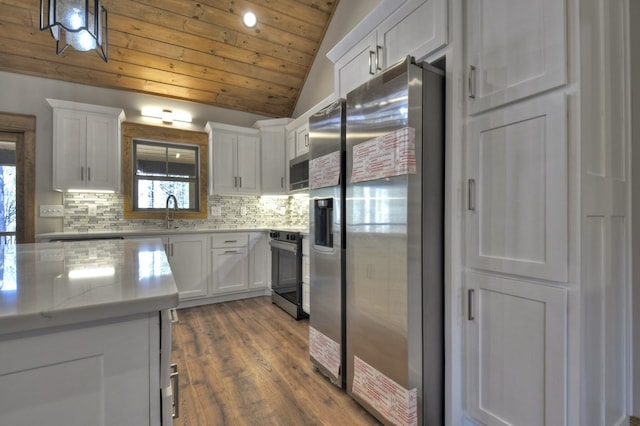 kitchen featuring tasteful backsplash, appliances with stainless steel finishes, white cabinetry, and vaulted ceiling