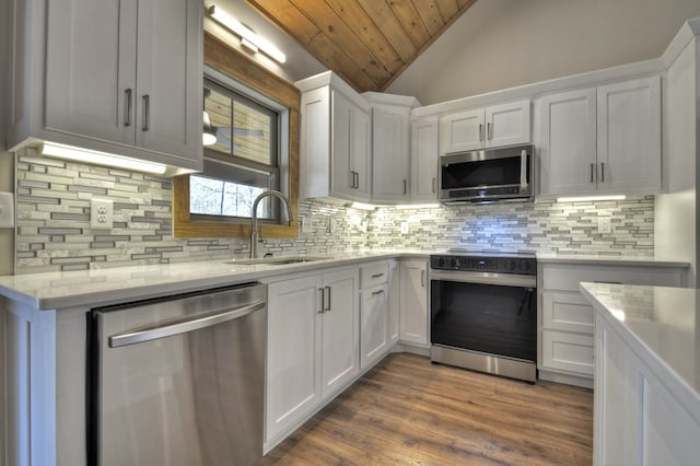 kitchen featuring dark wood finished floors, lofted ceiling, a sink, appliances with stainless steel finishes, and white cabinetry