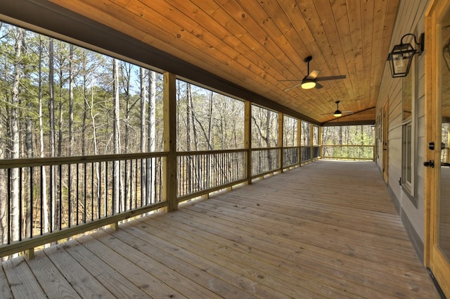 wooden terrace with a ceiling fan and a view of trees