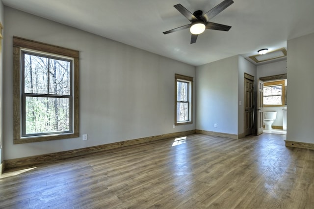 spare room with wood finished floors, a healthy amount of sunlight, baseboards, and ceiling fan