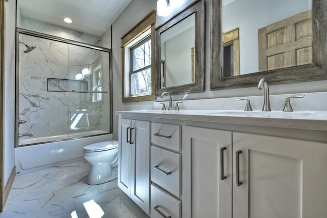 bathroom with double vanity, a sink, marble finish floor, toilet, and combined bath / shower with glass door