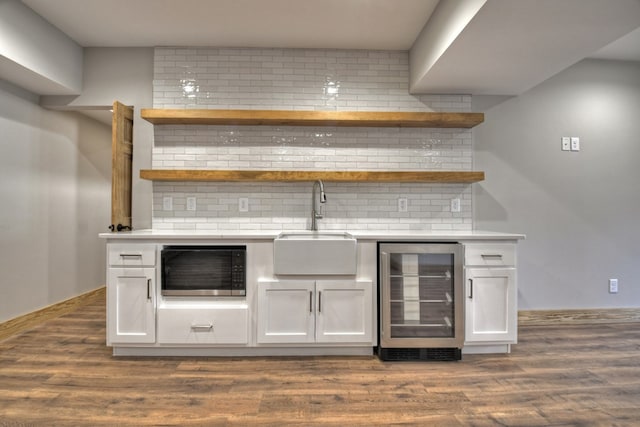 bar featuring a sink, wine cooler, decorative backsplash, bar, and dark wood-style flooring