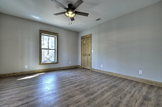 spare room with a ceiling fan, visible vents, wood finished floors, and baseboards