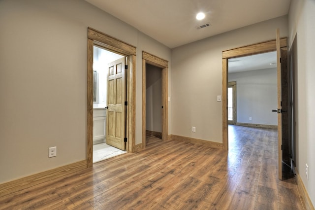 unfurnished room featuring wood finished floors, visible vents, and baseboards