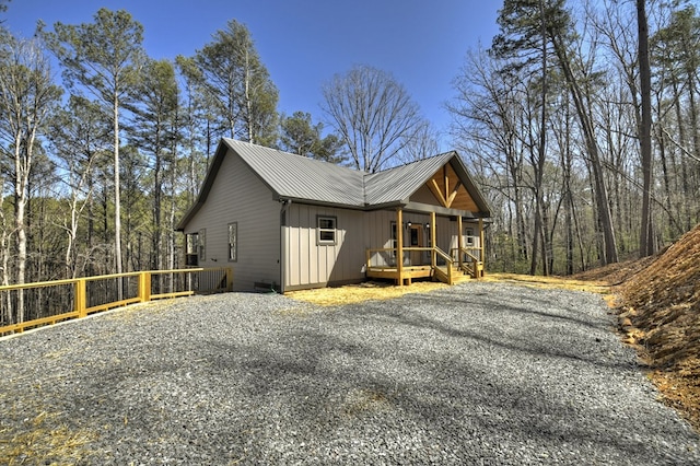 view of side of property featuring metal roof, board and batten siding, and fence