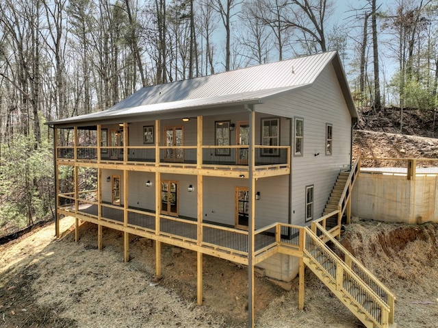 back of property with a wooden deck, metal roof, stairs, and a standing seam roof