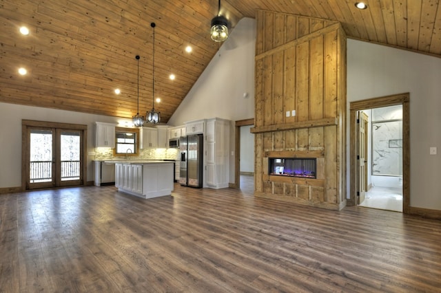 kitchen with dark wood finished floors, appliances with stainless steel finishes, white cabinetry, open floor plan, and a center island