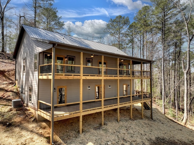 rear view of property with metal roof, cooling unit, a deck, and a ceiling fan