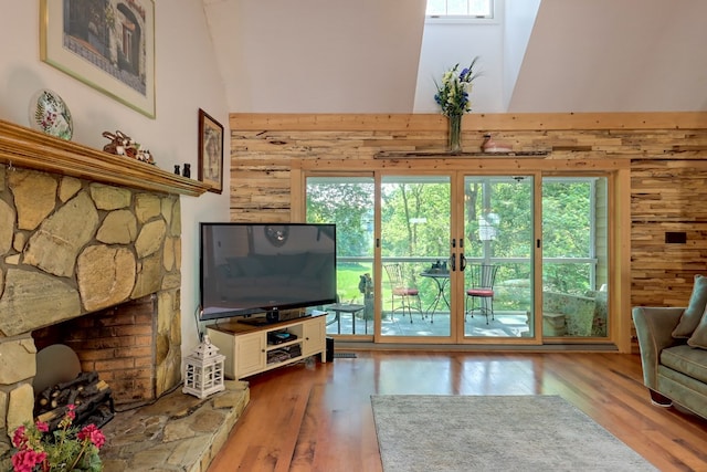 living room featuring a towering ceiling, a healthy amount of sunlight, and hardwood / wood-style flooring