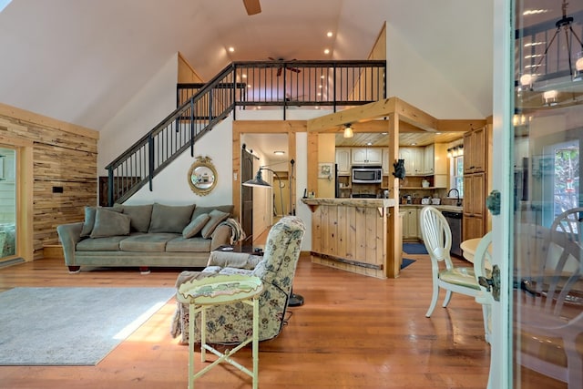 living room with light hardwood / wood-style floors, sink, and high vaulted ceiling