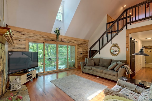 living room with a high ceiling, light wood-type flooring, and a healthy amount of sunlight