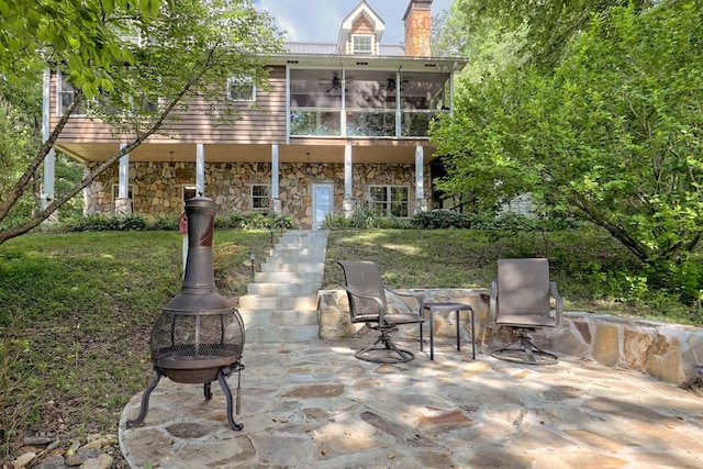 exterior space featuring a sunroom, an outdoor fire pit, and a patio