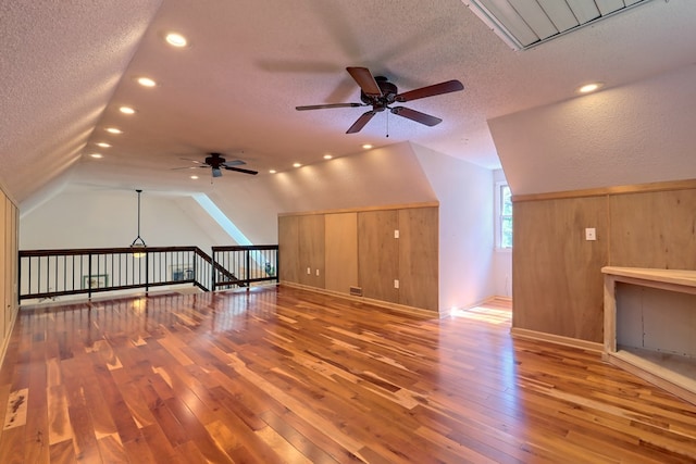 additional living space with ceiling fan, wood-type flooring, a textured ceiling, and vaulted ceiling