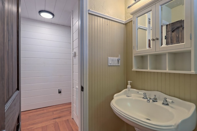 bathroom featuring wood walls, wood-type flooring, and sink