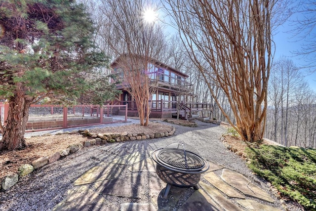 view of property's community with an outdoor fire pit, fence, a wooden deck, and a patio