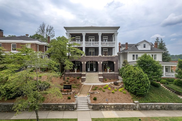 view of front of property with covered porch, stairs, and a balcony