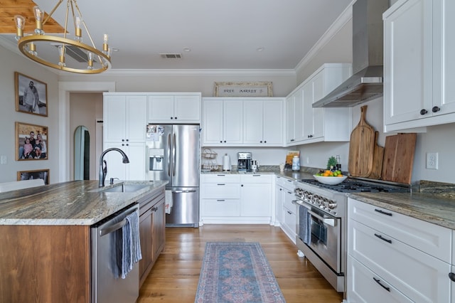 kitchen with stone countertops, a sink, white cabinetry, appliances with stainless steel finishes, and wall chimney exhaust hood