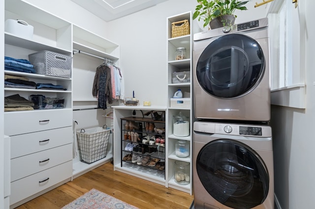 clothes washing area with laundry area, light wood-style floors, and stacked washer / dryer