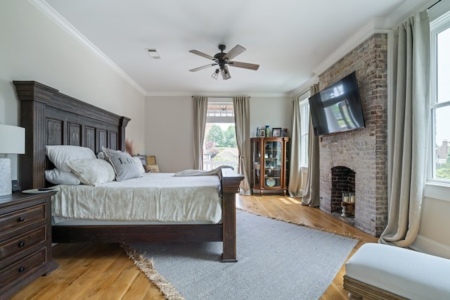 bedroom featuring light wood-type flooring, a brick fireplace, and ornamental molding