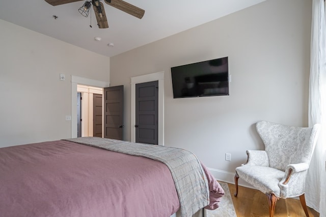 bedroom featuring ceiling fan, baseboards, and wood finished floors