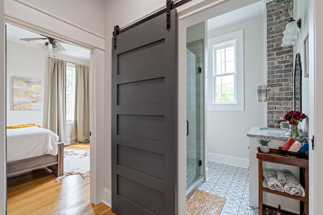 ensuite bathroom with a stall shower, connected bathroom, a ceiling fan, and baseboards