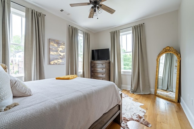 bedroom featuring light wood finished floors, a ceiling fan, visible vents, and baseboards