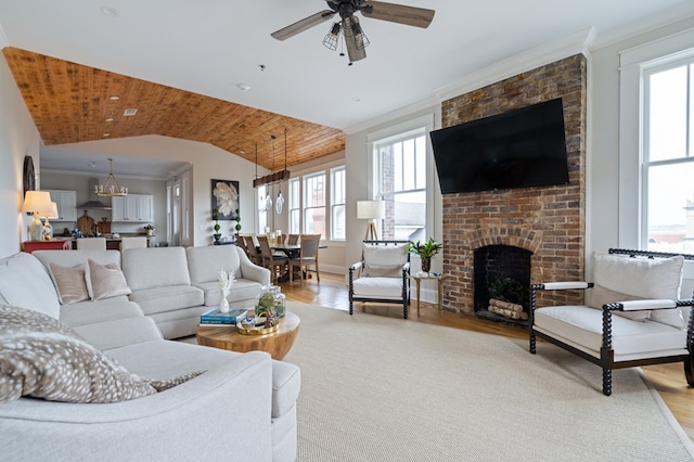 living room featuring lofted ceiling, light wood-style flooring, a fireplace, and crown molding