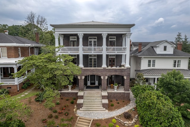 neoclassical / greek revival house with a balcony, covered porch, and stairway