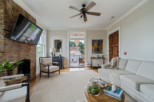 living room featuring a fireplace, visible vents, ornamental molding, a ceiling fan, and wood finished floors