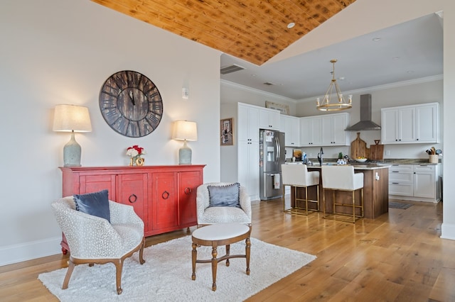 interior space featuring vaulted ceiling, light wood finished floors, visible vents, and crown molding