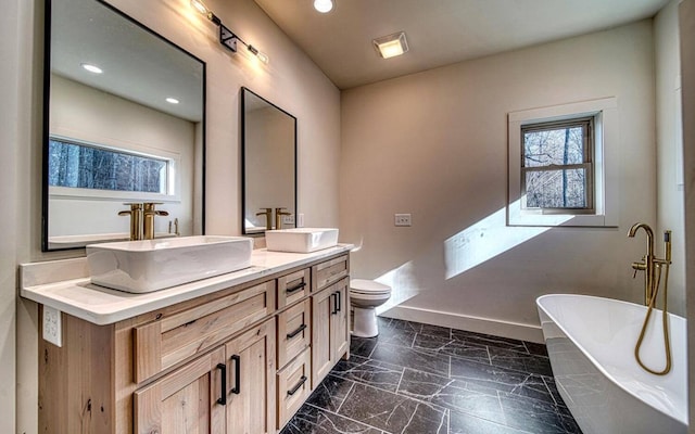 bathroom featuring vanity, toilet, and a tub to relax in