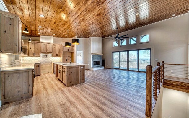 kitchen featuring hanging light fixtures, sink, wood ceiling, and an island with sink