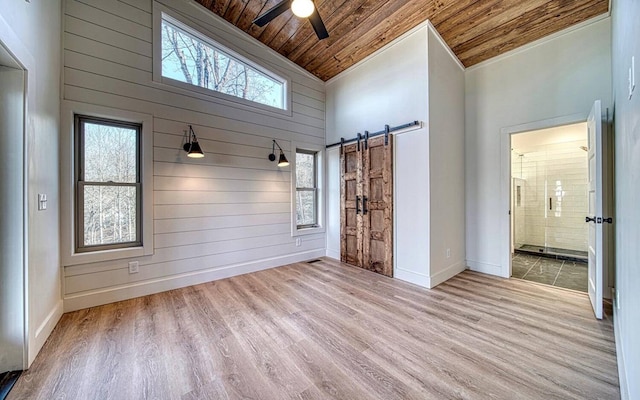 mudroom with light hardwood / wood-style floors, a barn door, wood ceiling, and high vaulted ceiling