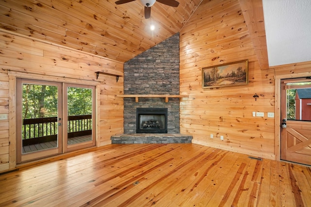 unfurnished living room featuring ceiling fan, high vaulted ceiling, a fireplace, hardwood / wood-style floors, and wood walls