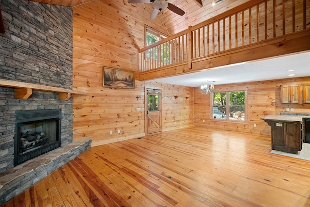 unfurnished living room featuring wood walls, light hardwood / wood-style floors, and high vaulted ceiling