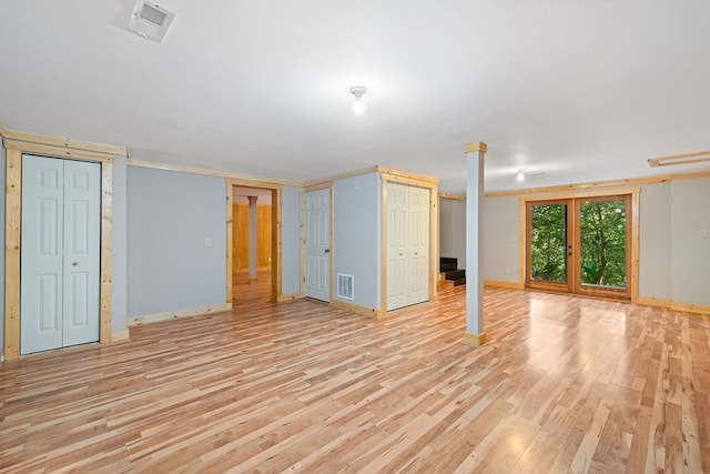 basement with french doors and light hardwood / wood-style flooring