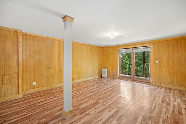 unfurnished room featuring wood-type flooring and wooden walls