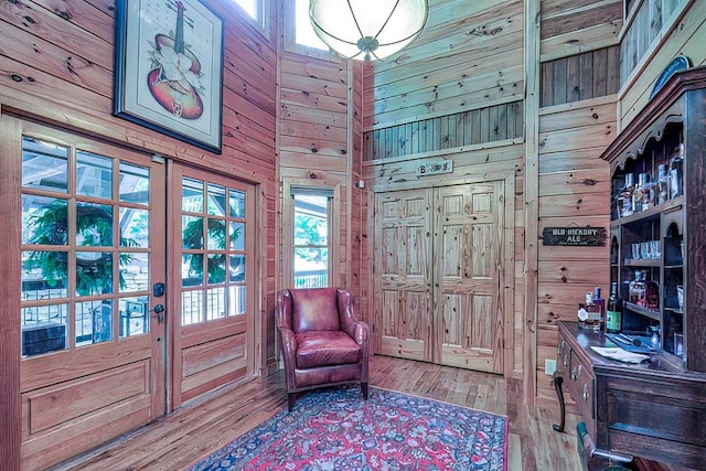 entryway featuring wooden walls, a towering ceiling, and hardwood / wood-style flooring