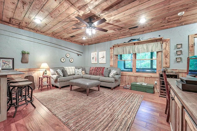 living room with ceiling fan, light hardwood / wood-style flooring, wood walls, and wooden ceiling