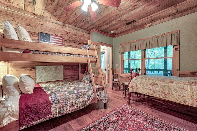 bedroom with wood-type flooring, wood walls, ceiling fan, and wooden ceiling