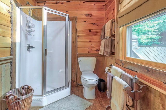 bathroom featuring wood walls, a shower with door, hardwood / wood-style floors, radiator heating unit, and toilet