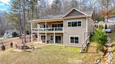 rear view of house featuring a yard, a patio area, a balcony, and a fire pit