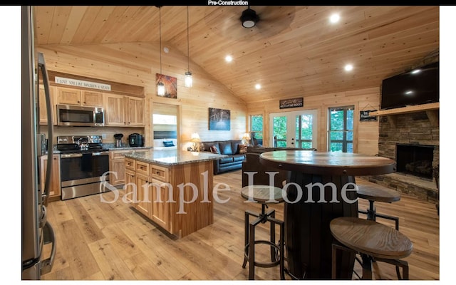 kitchen with wood walls, wooden ceiling, a kitchen island, stainless steel appliances, and light stone countertops