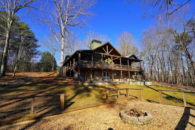 rear view of property with a wooden deck and a fire pit