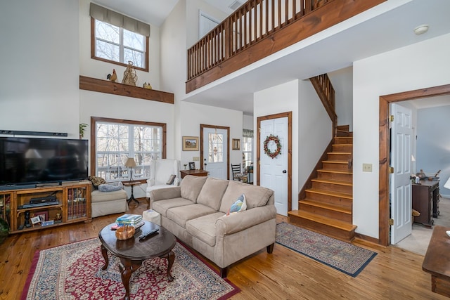 living room with plenty of natural light, a high ceiling, and light wood-type flooring