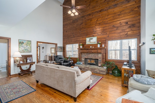 living room featuring a fireplace, high vaulted ceiling, ceiling fan, and light wood-type flooring